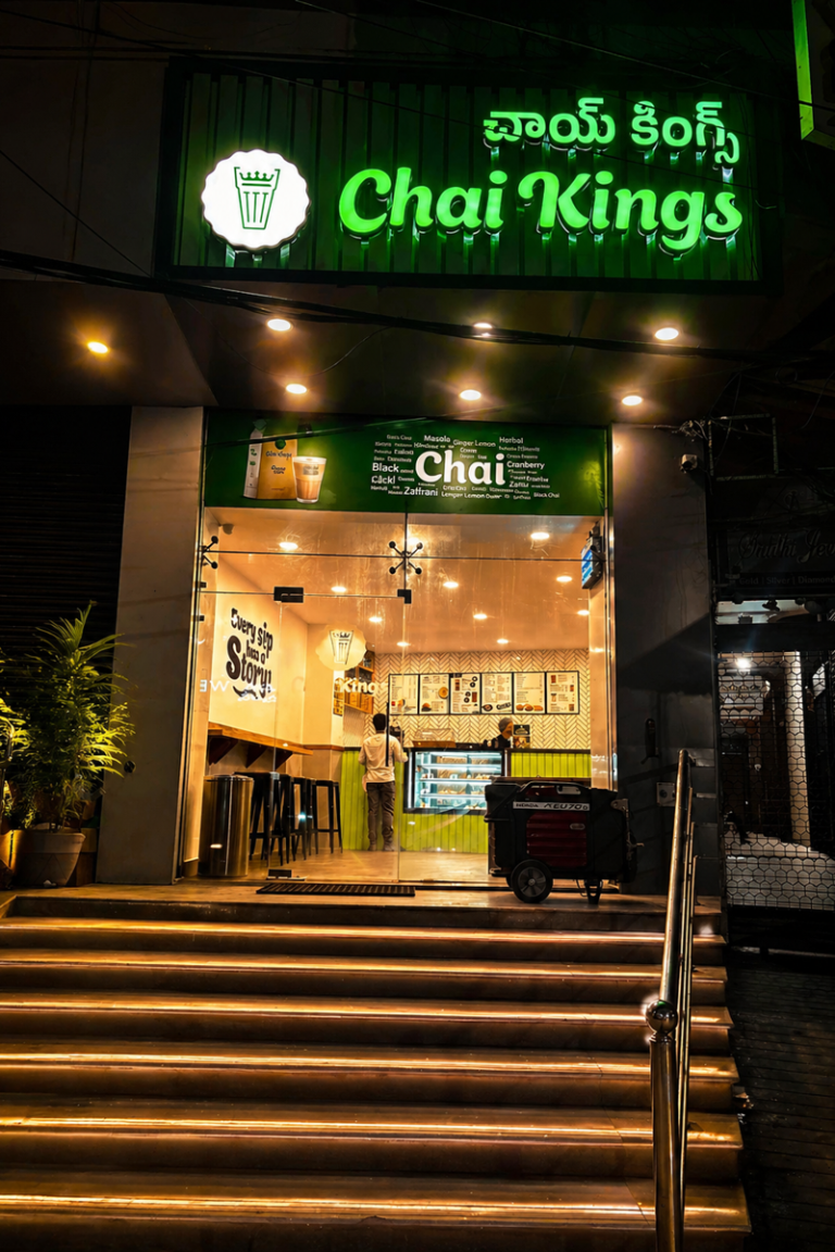 Chai Kings Ameerpet, Hyderabad outlet at night with glowing green signage, warmly lit entrance, and inviting storefront view from the staircase.