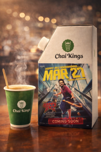 Chai Kings chai flask with Happy Raj movie branding next to a glass of tea on a wooden table, highlighting promotional packaging for film marketing.