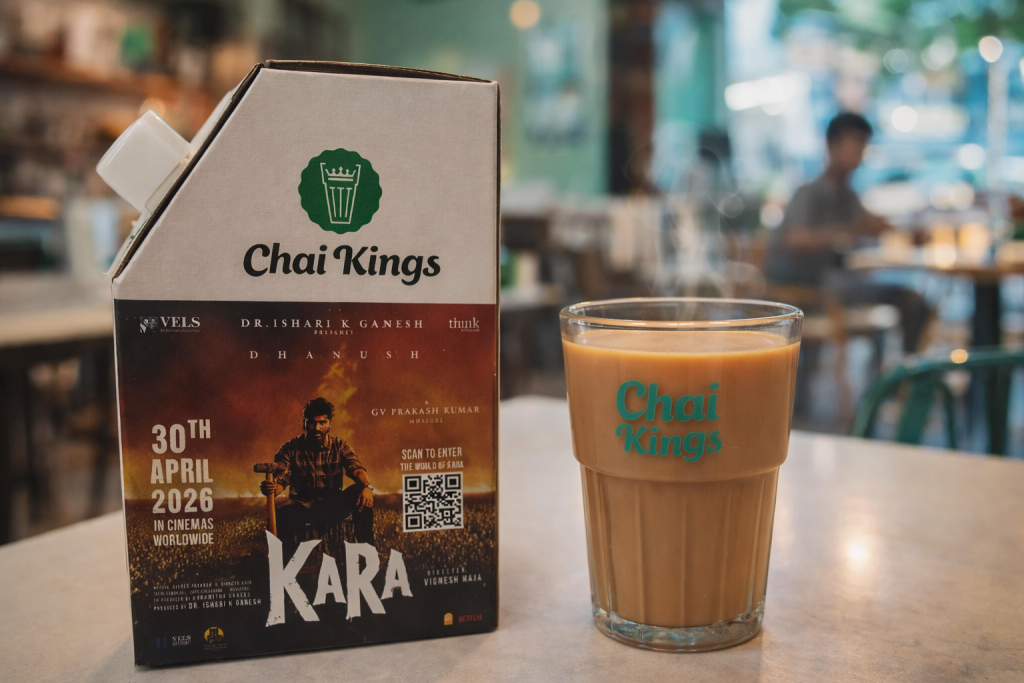 Chai Kings 300ml chai flask featuring Kara movie promotion with Dhanush, placed next to a steaming glass of chai at a Chai Kings store in Chennai