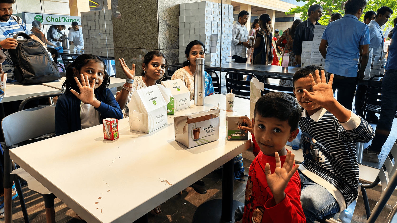 Families and children enjoying Chai Kings catering services at a community event in Chennai with tea, snacks, and takeaway meal boxes.