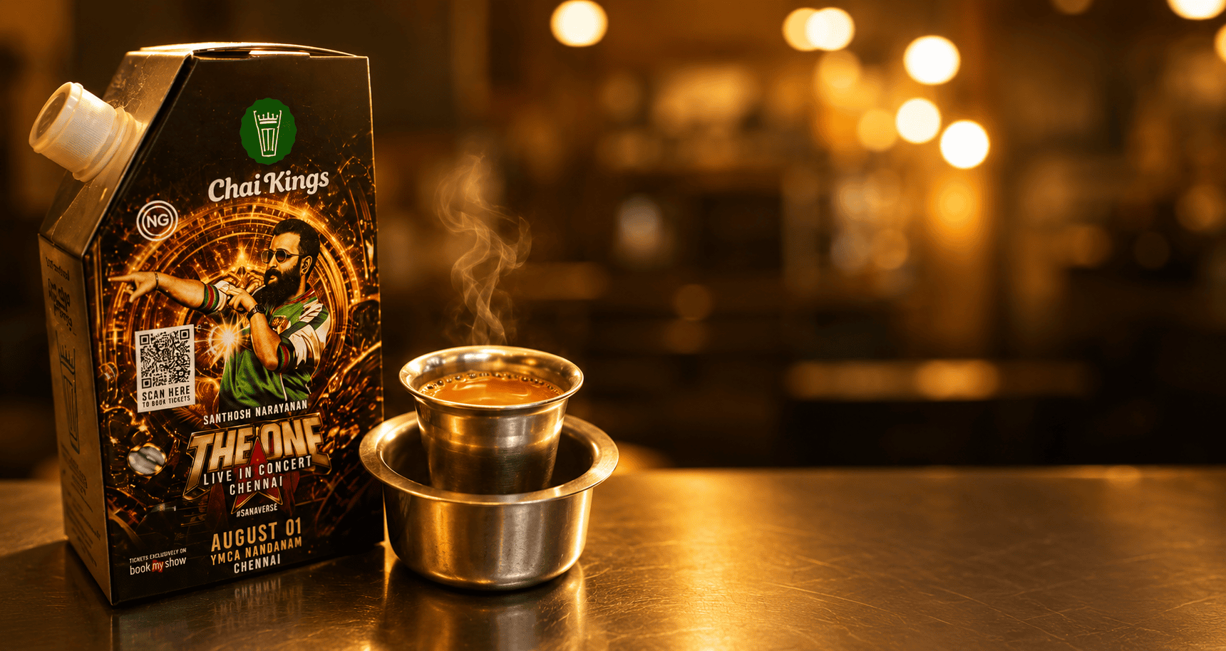 Chai Kings mini flask featuring Santhosh Narayanan's The One Live in Concert Chennai artwork placed beside a hot cup of chai in a café.